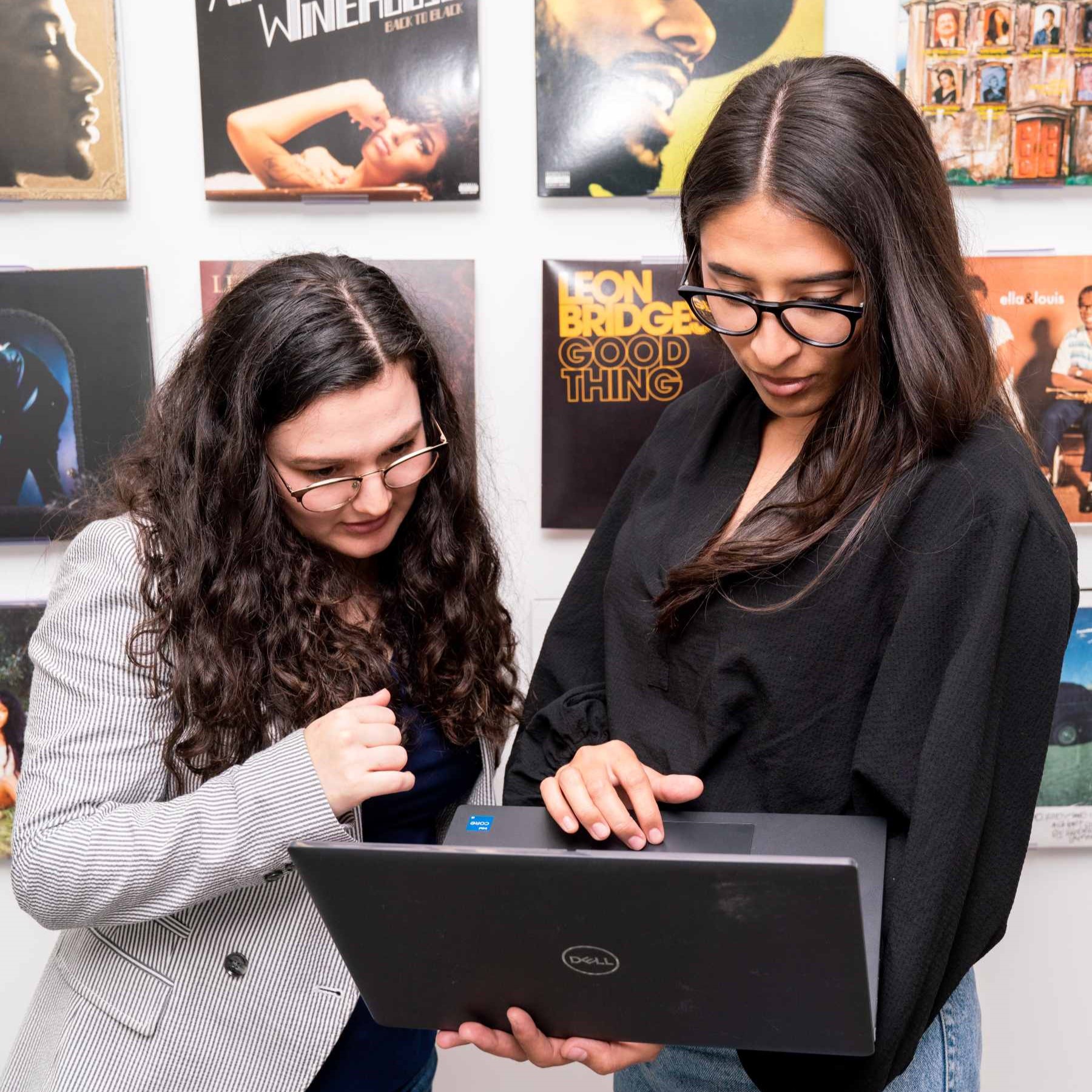 A photo of CPA Gaby and CPA trainee Mackenzie reviewing a client tax file in front of Gaby’s vinyl record display.